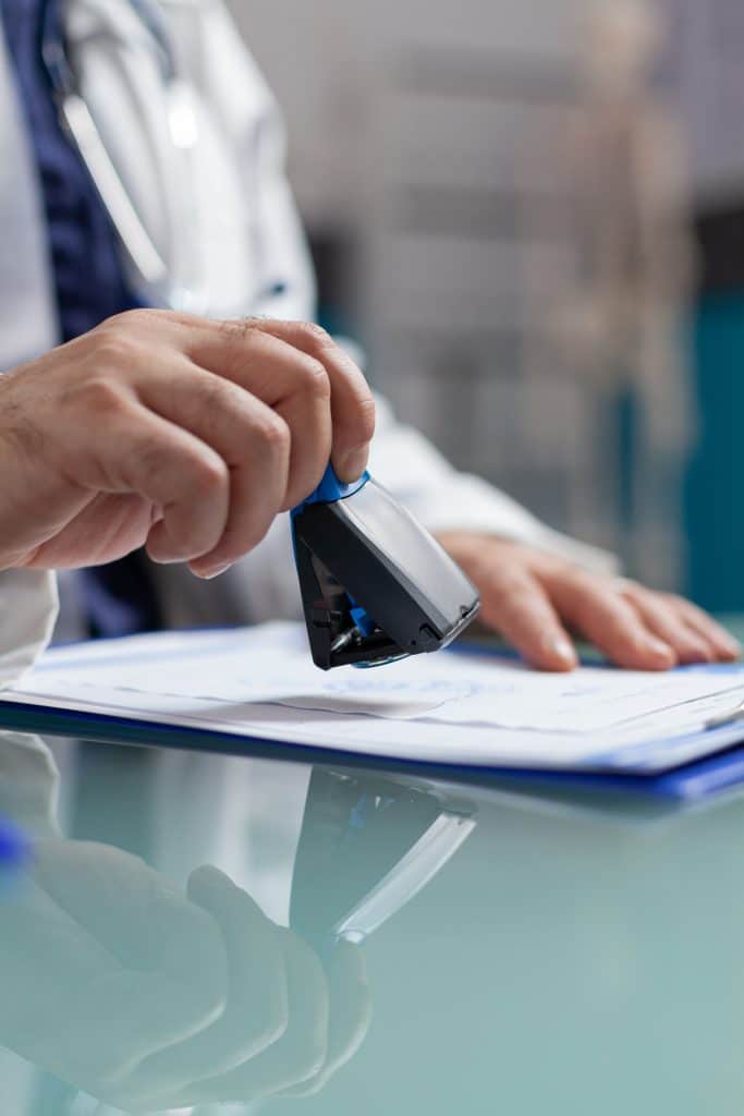 Doctor holding medical stamp to put on prescription paper